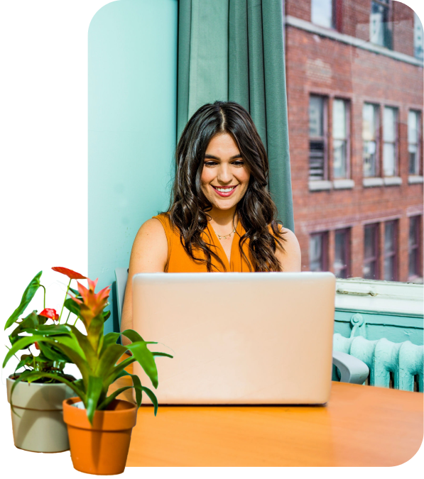 A woman smiling while working at a laptop